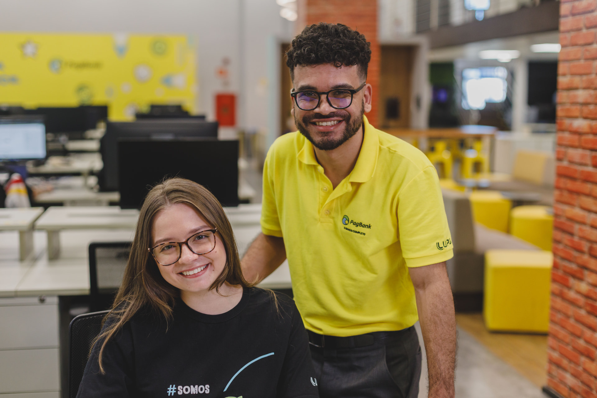 PagTalents em pé e sentada colaborando no escritório PagBank