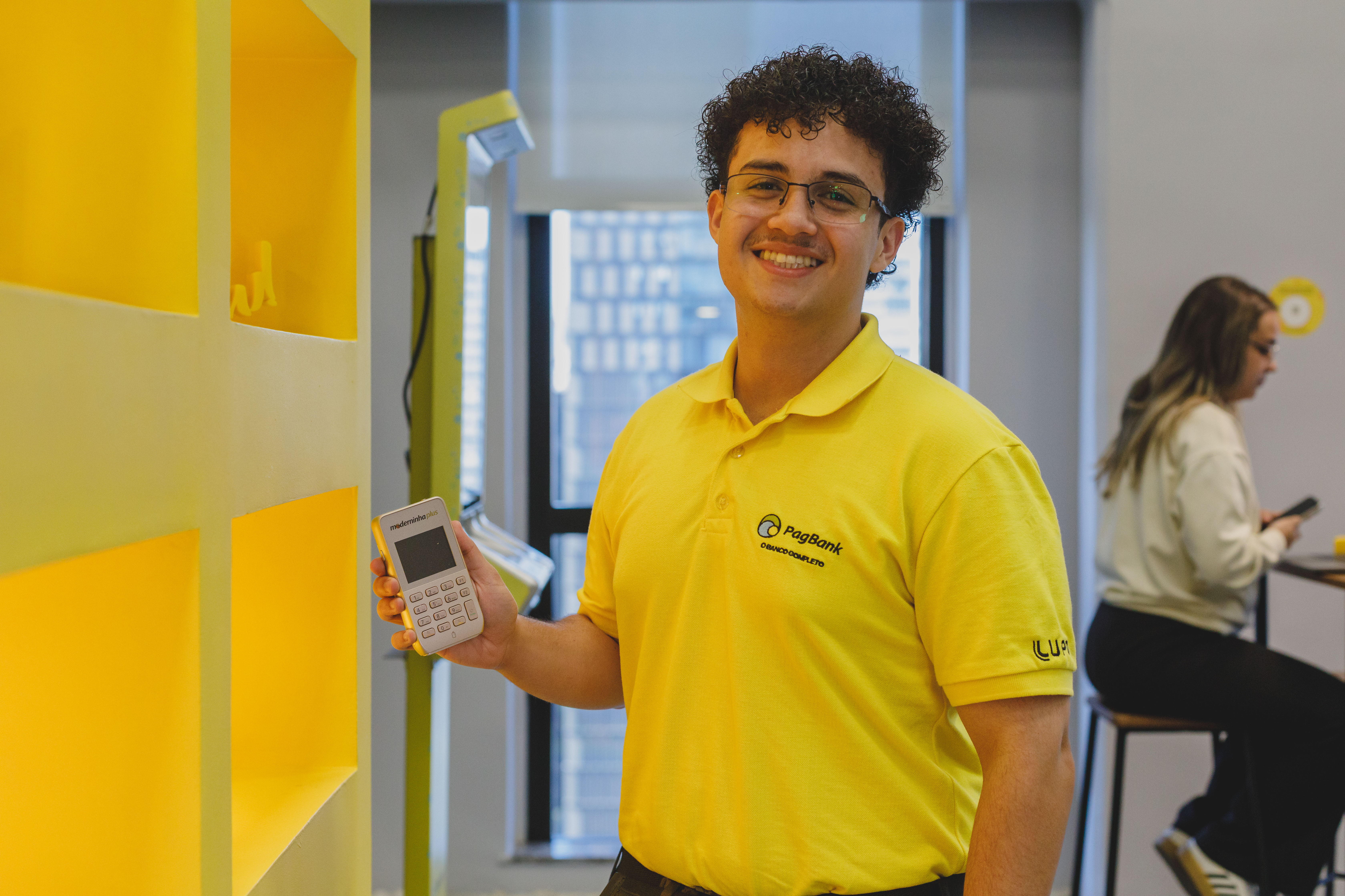 Pedro Henrique, PagTalent de Operações TI, segurando uma maquininha PagBank